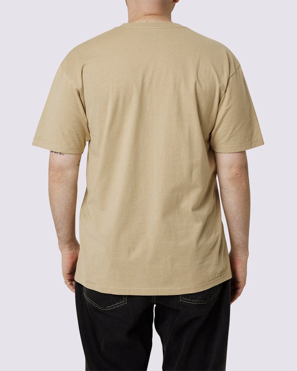 Back view of a beige Vans t-shirt worn by a man, showcasing its plain design and relaxed fit, paired with black pants.