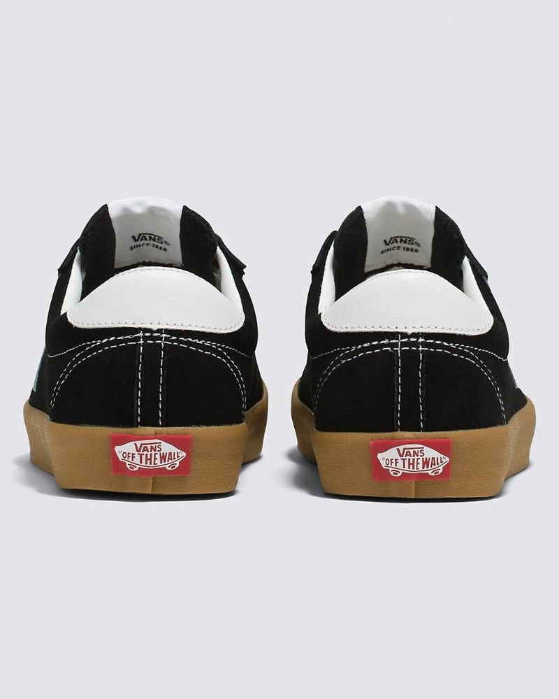 Rear view of black low-top Vans sneakers with white accents, gum rubber soles, and red "Vans Off The Wall" branding on the heel.