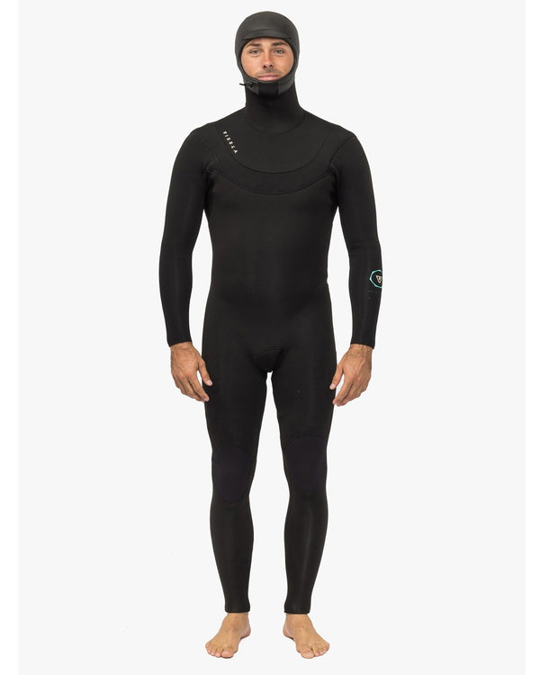 Man wearing a black full-body wetsuit with an integrated hood, standing barefoot against a white background.