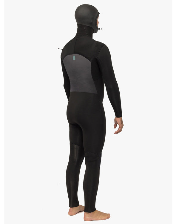 Man wearing a black full-body wetsuit with an integrated hood, shown from the back, standing barefoot.