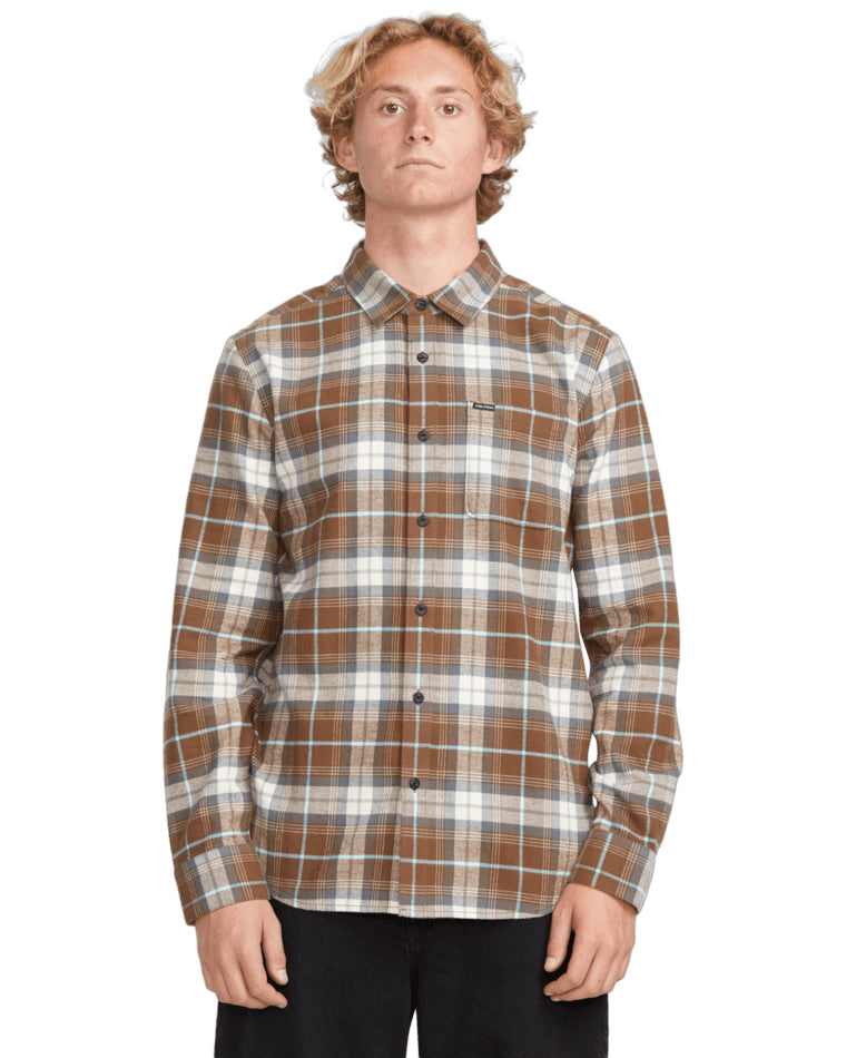 Male model wearing a brown and white plaid button-up shirt with a front pocket, paired with black pants.