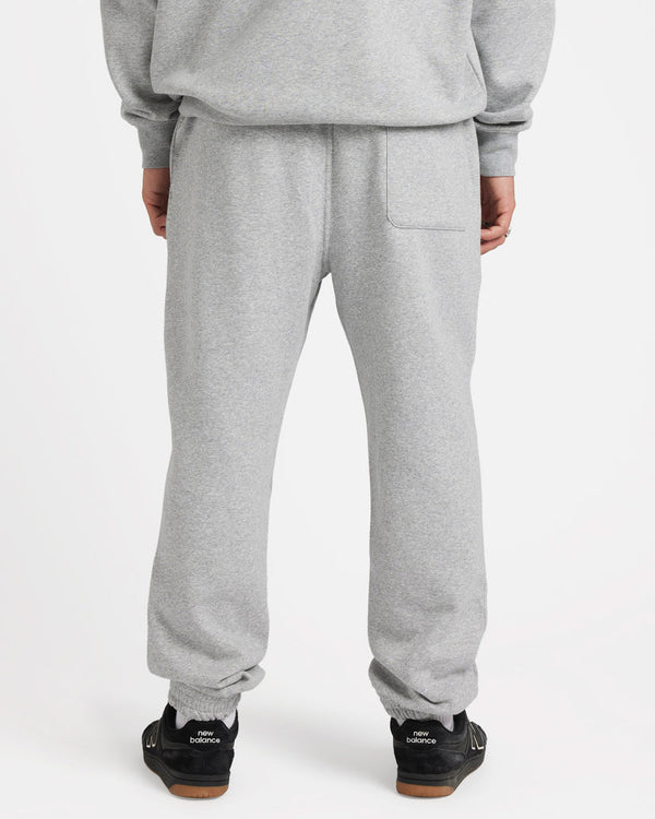 Back view of model wearing light grey sweatpants with an elastic waistband and single back pocket, paired with sneakers.