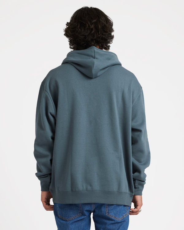 Back view of a male model wearing a blue-grey Volcom hoodie with a relaxed fit, hood down, and paired with blue jeans.