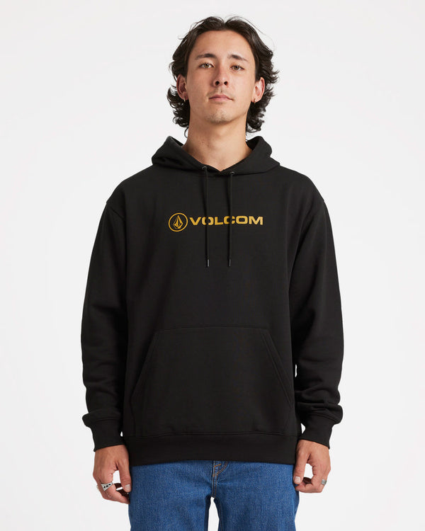 Model wearing a black Volcom hoodie with gold logo on the chest, drawstring hood, and kangaroo pocket, paired with jeans.