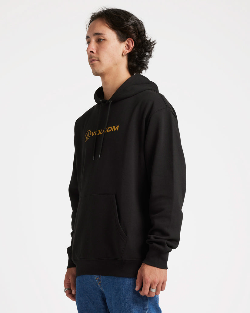 Side view of a model wearing a black Volcom hoodie with a gold logo, kangaroo pocket, and drawstring hood, paired with jeans.