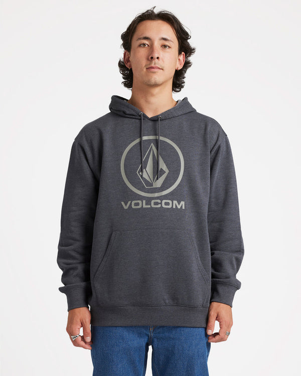 Male model wearing a dark grey Volcom hoodie with a large logo on the chest, paired with blue jeans, standing against a white backdrop.