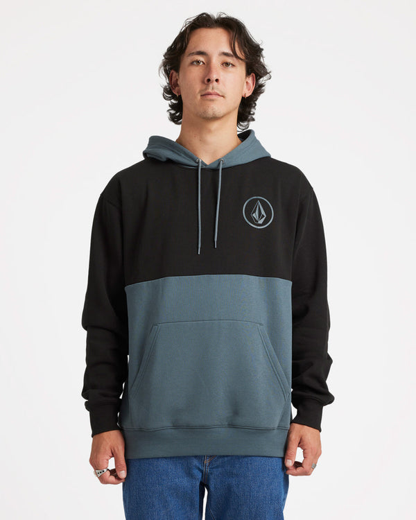 Male model wearing a two-tone Volcom hoodie with black upper and blue-grey lower half, featuring a front pocket and logo emblem.