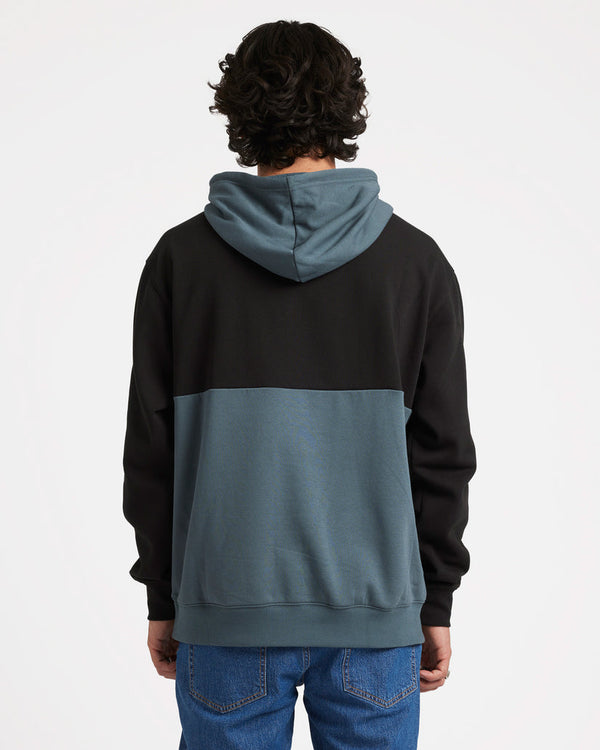 Back view of a male model wearing a two-tone Volcom hoodie with black upper and blue-grey lower half, featuring a hood.