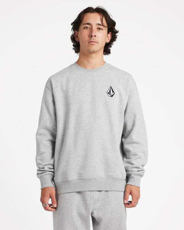 Male model wearing a light grey crewneck sweatshirt with a small Volcom logo on the chest, paired with matching sweatpants.