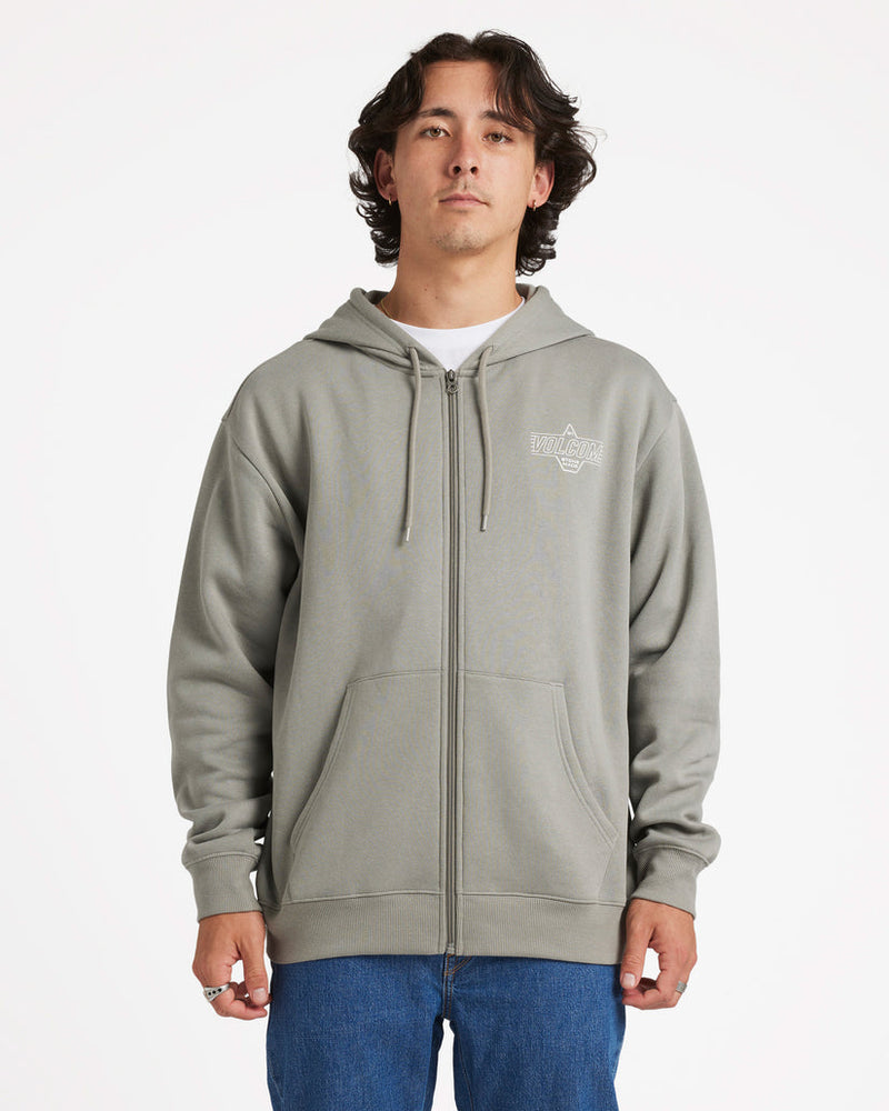 Model wearing a light grey Volcom zip-up hoodie with a small chest logo, drawstrings, and front pockets, paired with jeans.