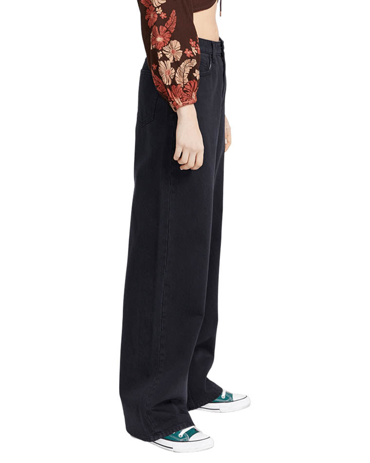 Side view of high-waisted black wide-leg jeans paired with a floral cropped top and teal sneakers for a casual, stylish look.