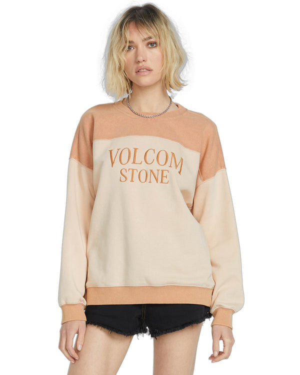 Woman wearing a color-blocked Volcom Stone sweatshirt in warm beige and peach tones, paired with black denim shorts.