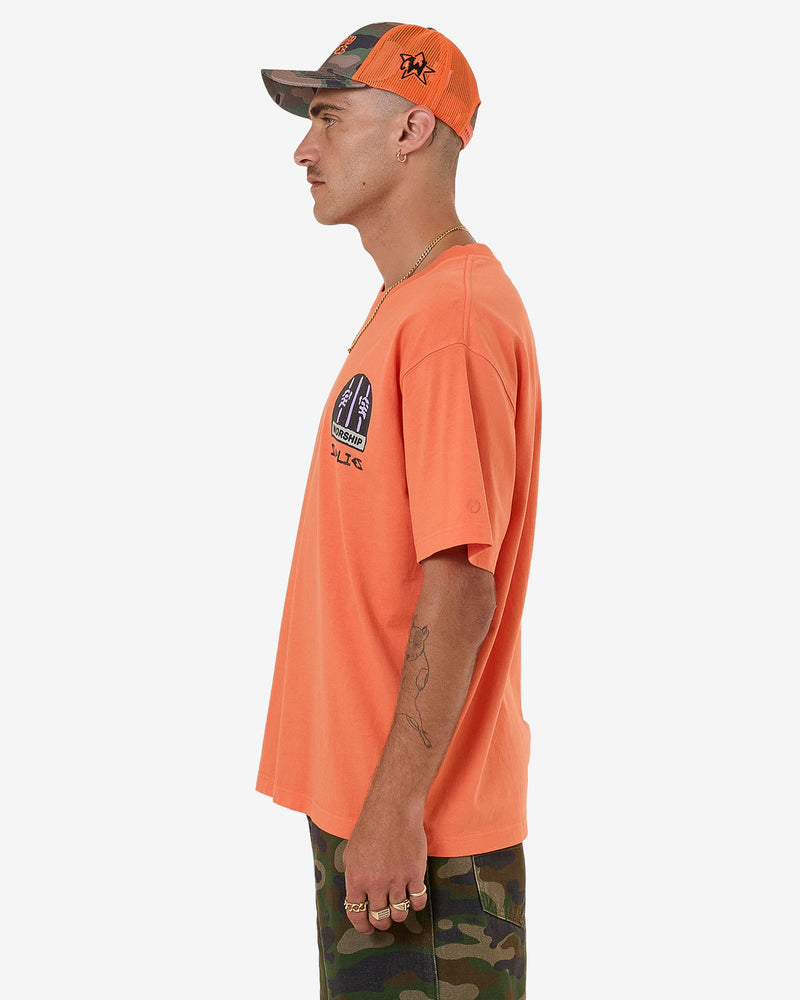 Side view of orange graphic tee with chest print and loose fit