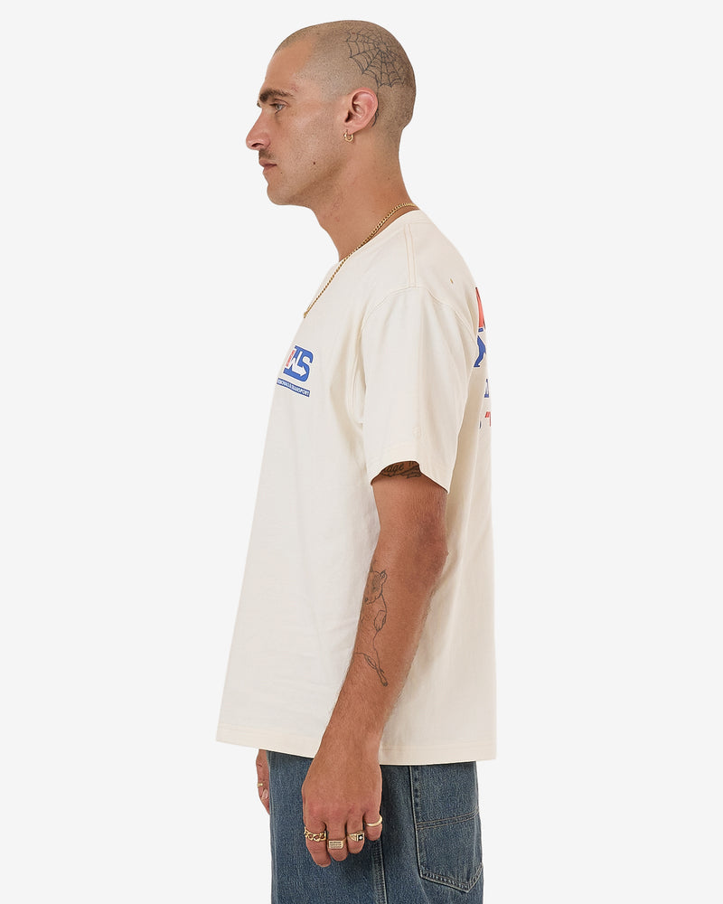 Cream short sleeve T-shirt with small blue and red chest logos, side profile view.