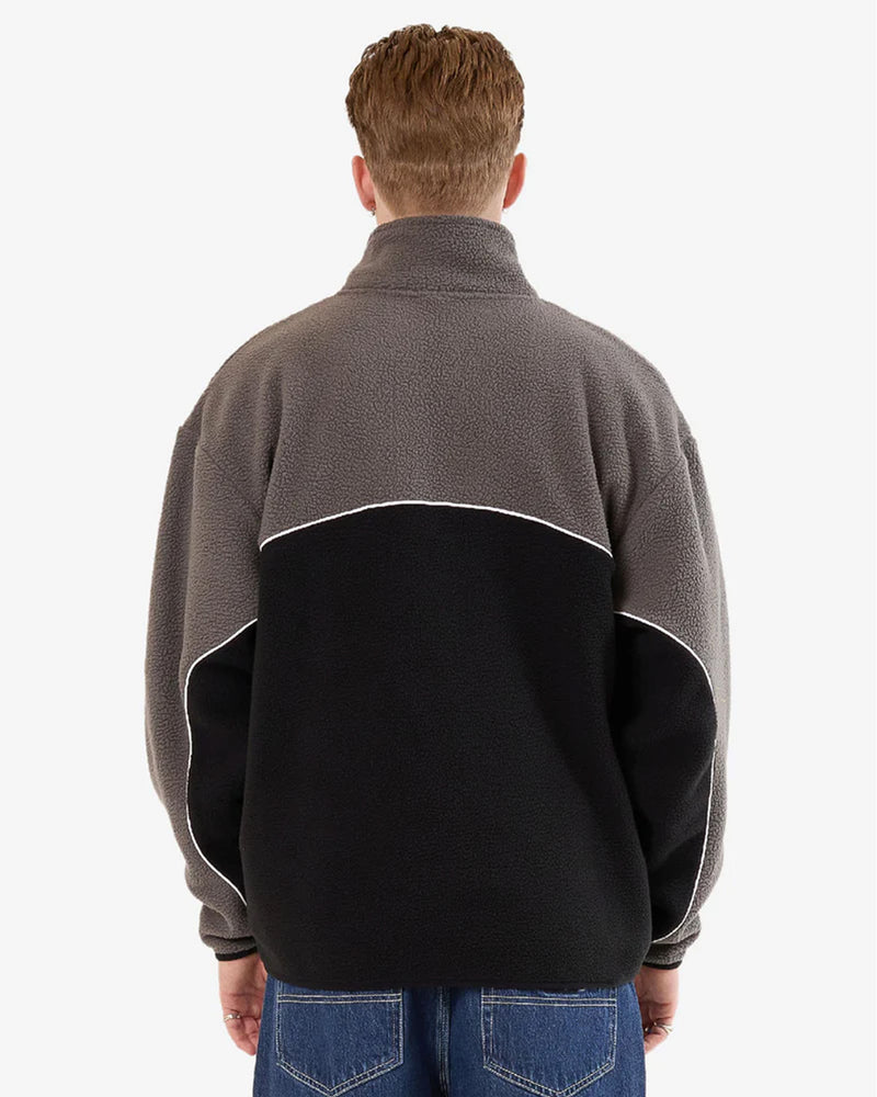 Back view of the Worship quarter-zip fleece showing contrast black and grey paneling with white piping across the shoulders and sleeves.