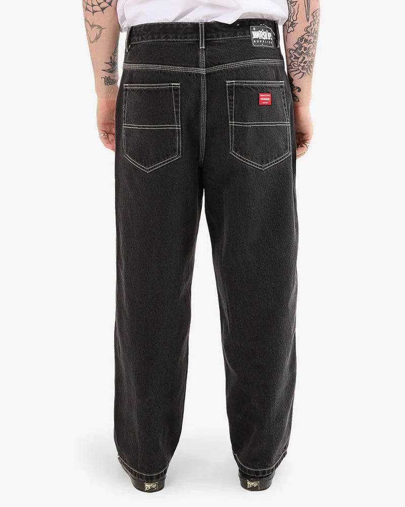 Back view of men's black jeans featuring contrast stitching and red Worship patch.