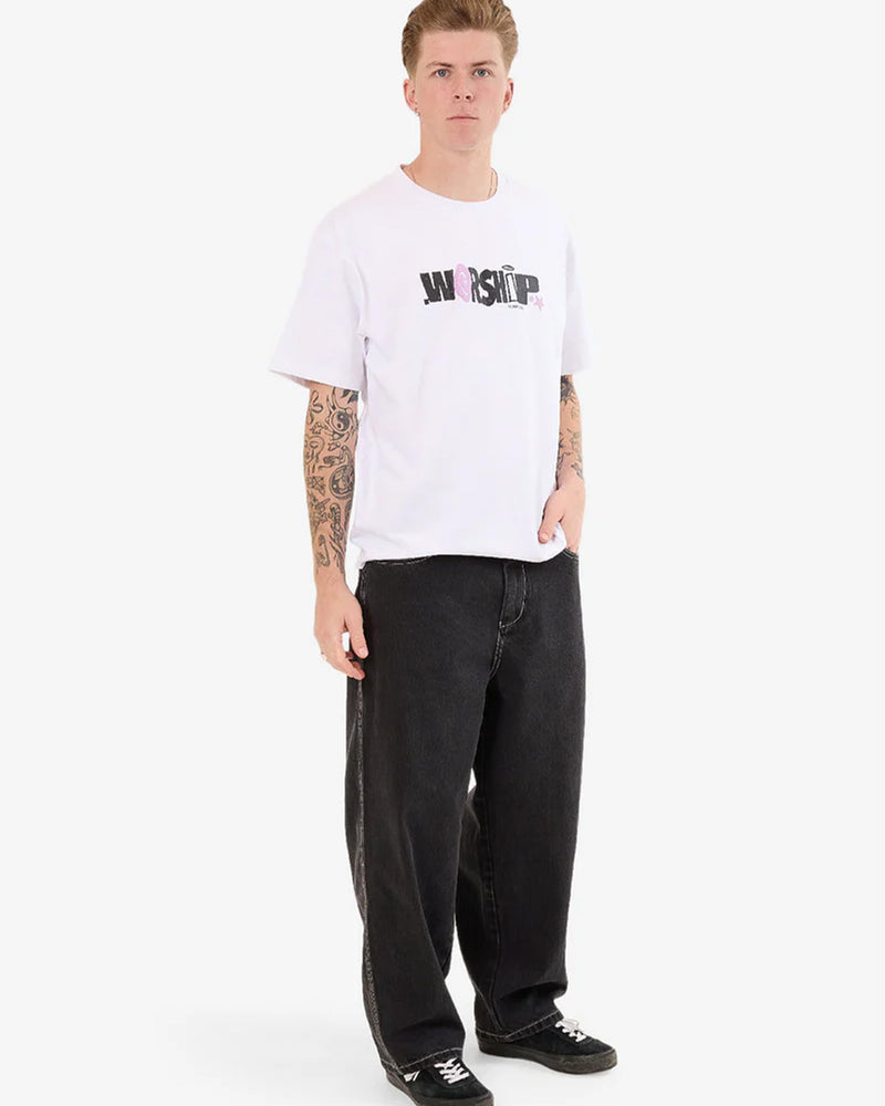 Full body angled view of model wearing black jeans with a white Worship tee.