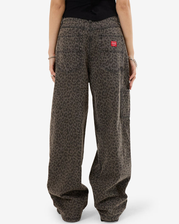 Back view of baggy, wide-leg leopard print jeans with oversized patch pockets, utility side pocket, and red logo tag.