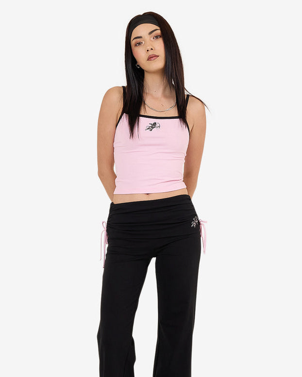 Front view of pink cropped tank top with black straps and "Worship" logo, worn with black drawstring pants.