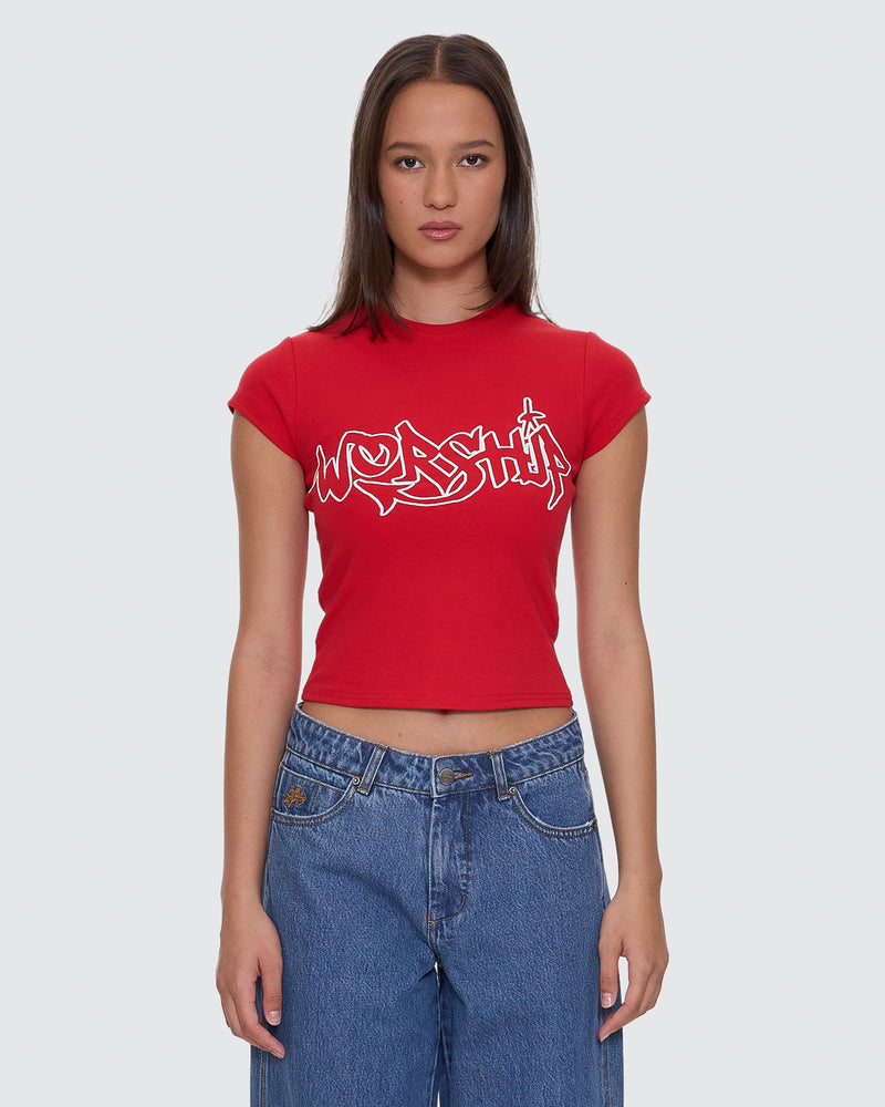 Red cropped t-shirt with white "Worship" graphic design on the front, paired with high-waisted denim jeans.