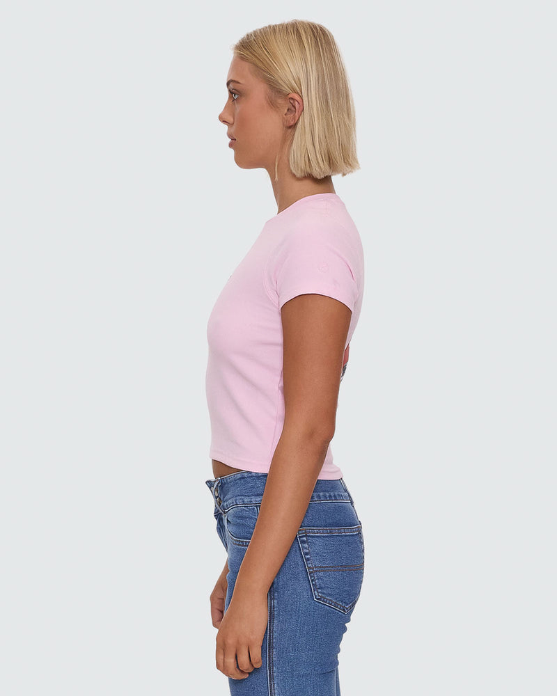 Side view of light pink fitted crop tee paired with blue denim jeans
