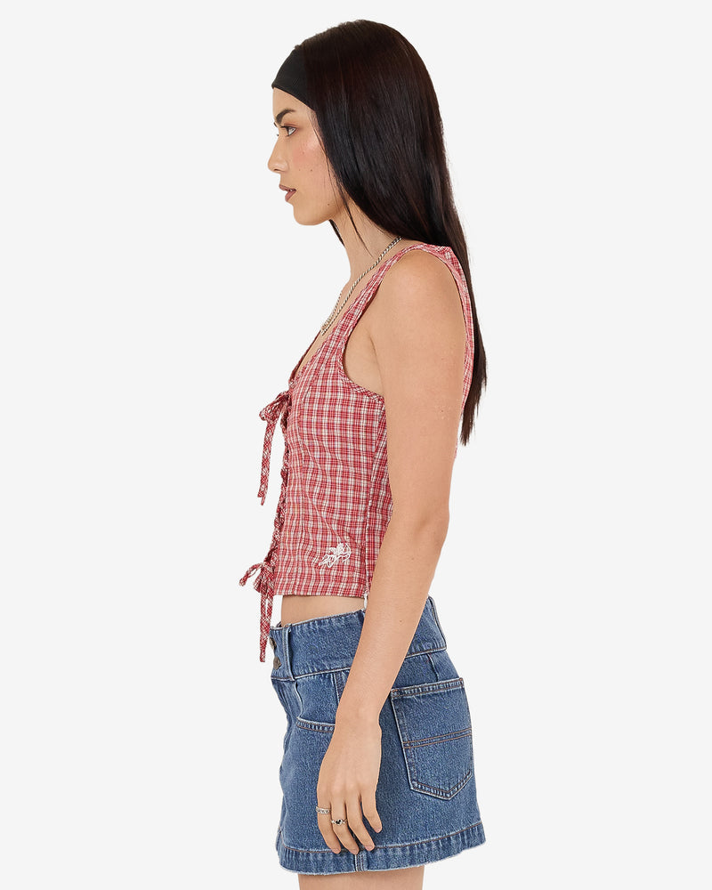 Side view of red check lace-up sleeveless top with cropped fit and scoop neckline