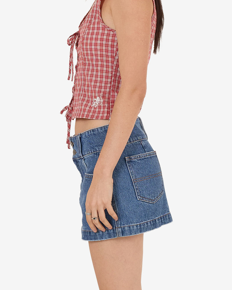Side view of blue denim mini skirt with pockets, styled with red check lace-up top