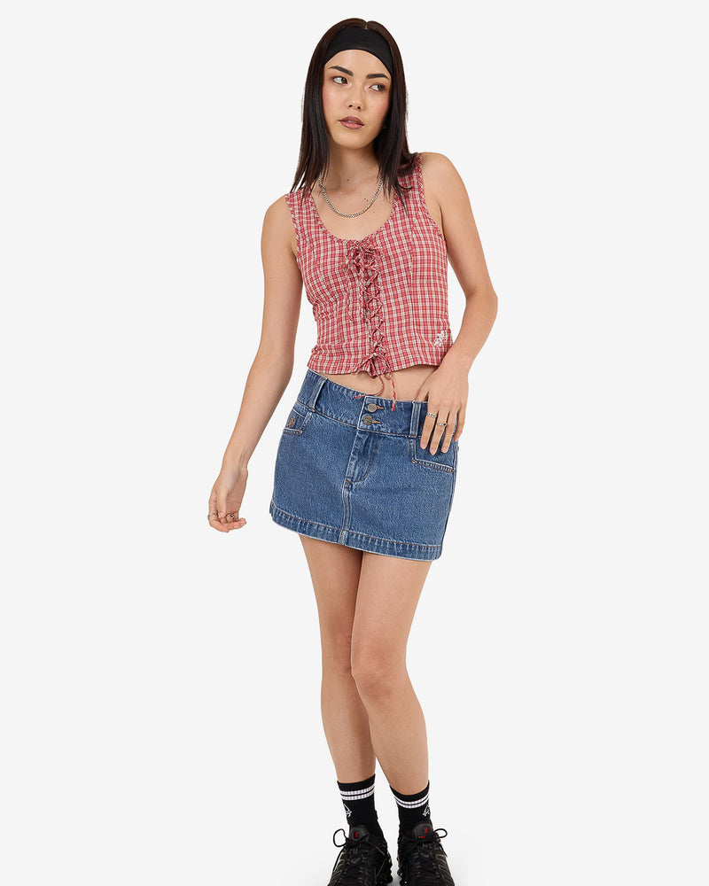 Model wearing blue denim mini skirt with red check lace-up top and black sneakers