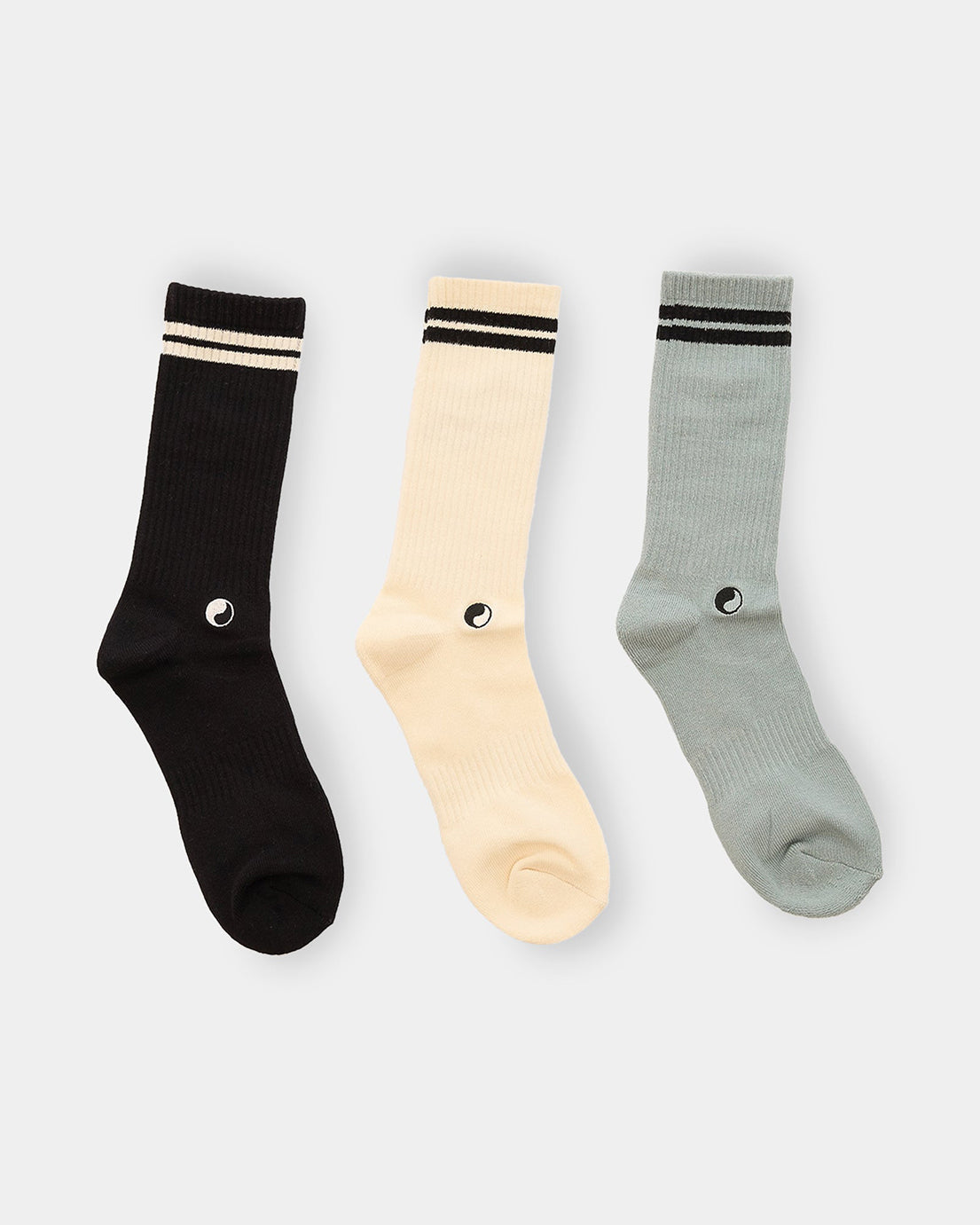 Back view of three-pack crew socks in black, cream and sage featuring Good Morning Tapes eye logo above heel.