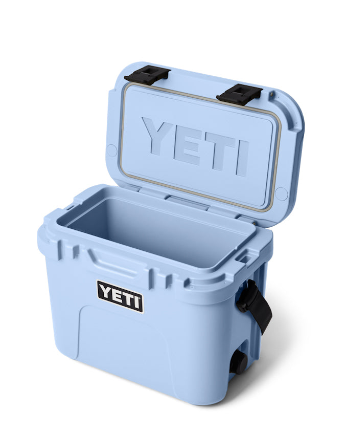 Light blue YETI hard cooler with an open lid, black latches, and a durable design, perfect for outdoor adventures.