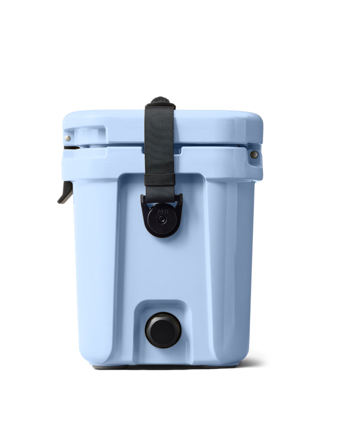 Side view of a light blue YETI hard cooler with a black strap, drain plug, and secure latch for durability and portability.