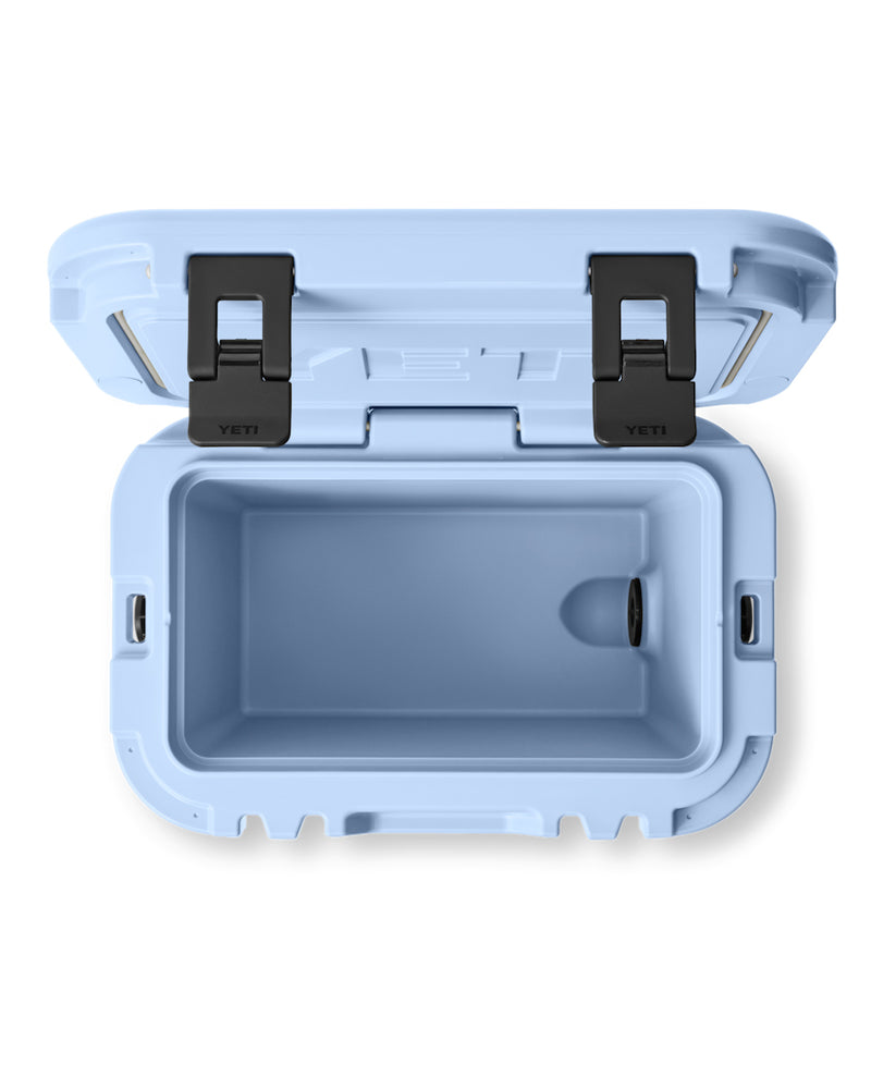 Top view of an open light blue YETI hard cooler with black latches, showing its spacious insulated interior and drain plug.